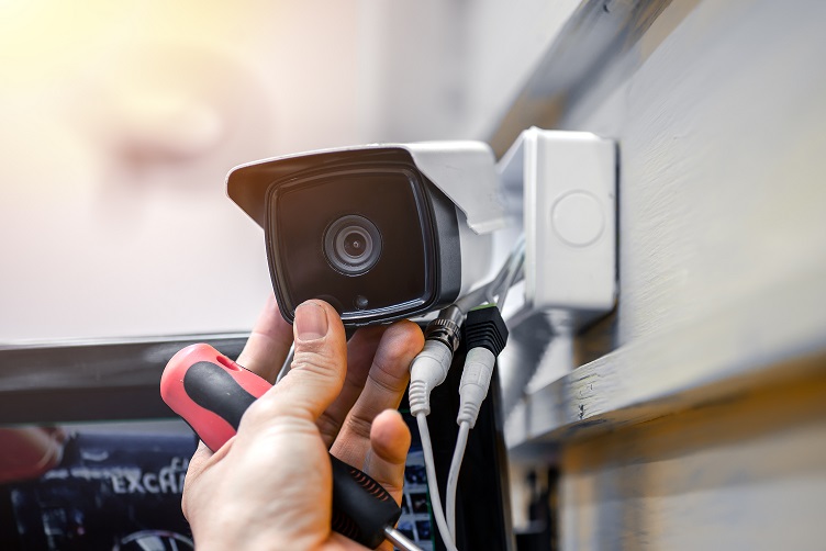 Close-up of surveillance camera installation, male hand holds cctv camera